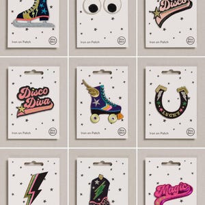Puede incluir: Una colección de nueve parches bordados termoadhesivos presentados en tarjetas blancas individuales con patrones de estrellas negras. Los diseños incluyen un patín de hielo, ojos móviles, un letrero de disco, un letrero de disco diva, un patín de ruedas, una herradura, un rayo, una bota vaquera y un letrero de magic.