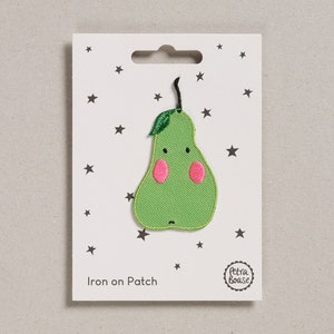 Könnte beinhalten: Ein grüner, birnenförmiger Aufbügler mit einem lächelnden Gesicht und rosa Wangen. Der Aufbügler befindet sich auf einer weißen Karte mit Sternenmuster und dem Text "Iron on Patch". Der Markenname "Petra Boase" ist ebenfalls sichtbar.