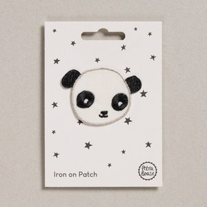 Può includere: Toppa da stirare con il viso di un panda bianco e nero con un contorno di glitter argentato. La toppa è su una carta bianca con un motivo a stelle nere e il testo "Iron on Patch" e "Petra Boase".