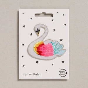May include: Iron-on patch featuring a white swan with colorful, embroidered feathers. The patch is on a white card with stars and the text "Iron on Patch" and "Petra Boase".
