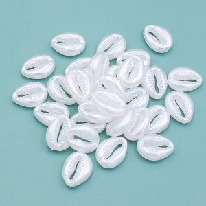 Pode incluir: Um monte de conchas brancas de forma oval com um acabamento liso e brilhante. As conchas estão dispostas em um padrão aleatório sobre um fundo azul claro.