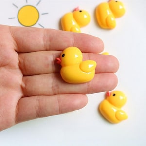 May include: Four yellow rubber duck figurines. The ducks are in various poses and have a glossy finish.