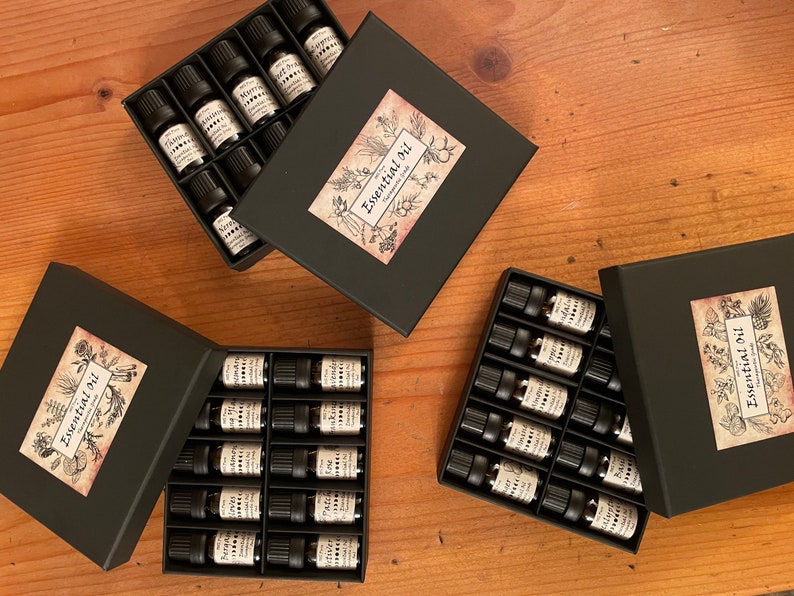 May include: Three black boxes filled with small glass bottles of essential oils. Each box has a label that says "Essential Oil" with a botanical illustration.