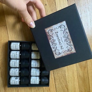 May include: A black box with a label that says "Premium Essential Oil" and contains 12 small glass bottles with labels listing different essential oils.