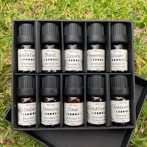 May include: A black box with 10 small glass bottles containing essential oils. The bottles are labeled with the names of the oils, including Sandalwood, Basil, Lemon, Peppermint, Ginger, Cedar, Jasmine, Sage, Eucalyptus, and Chamomile.