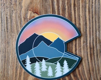 May include: A sticker featuring a stylized outline of the state of Colorado with a sunset scene over mountains and a forest of pine trees at the base.