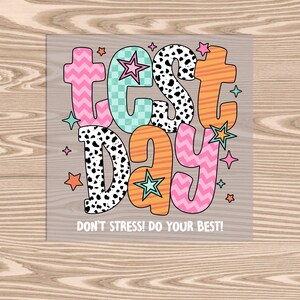 May include: A colorful graphic with the words "TEST DAY" in various patterns and colors, including pink zigzags, teal checkerboard, and orange stripes. The word "DAY" is in pink zigzags. The text "DON'T STRESS! DO YOUR BEST!" is below the main text.