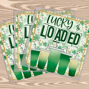 May include: Four green and white drink cups with straws and a green shamrock pattern. The cups are stacked on top of each other and have the text "Lucky & Loaded" on the top cup.