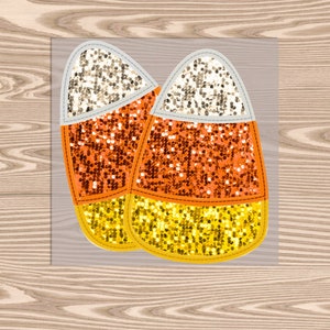 May include: Two candy corn shaped patches with gold, orange, and white glitter.