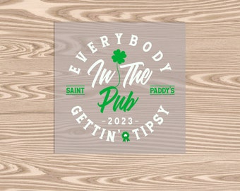 Peut inclure: Un cercle blanc avec le texte "Everybody in the Pub - 2023 - Gettin' Tipsy" avec un trèfle vert et les mots "Saint Paddy's" sur un fond gris clair.