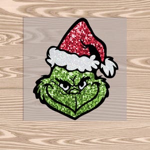 May include: A green and red glitter Grinch wearing a Santa hat. The Grinch is smiling with a mischievous expression.