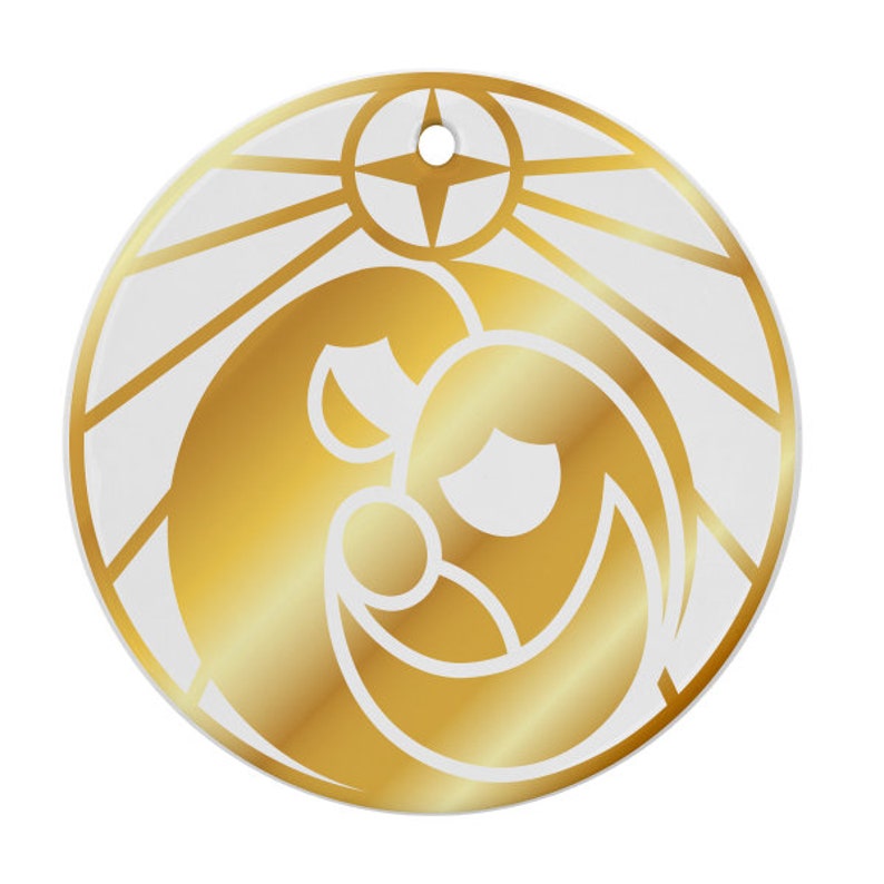 Puede incluir: Un adorno navide&ntilde;o dorado con fondo blanco. El adorno presenta una imagen estilizada de la Sagrada Familia, con Mar&iacute;a, Jos&eacute; y el ni&ntilde;o Jes&uacute;s. La imagen est&aacute; rodeada por un dise&ntilde;o de estrella.