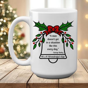 May include: White ceramic mug featuring a Christmas bell design with a red bow, green holly leaves, and red berries. The mug has the quote "A man doesn't get in a situation like this every day." from "It's A Wonderful Life."