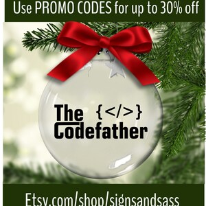 May include: A clear glass Christmas ornament with the text "The Codefather" and HTML code symbols. The ornament is adorned with a red bow and hangs on a Christmas tree. The Etsy shop URL is visible.