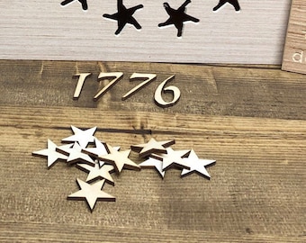 Puede incluir: Un letrero de madera con el año 1776 tallado en él. Hay varias pequeñas estrellas de madera esparcidas alrededor del letrero.