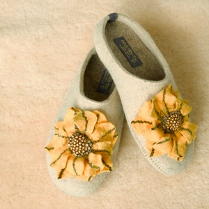 May include: Pair of beige felt slippers with yellow felt sunflower embellishments and brown bead accents. The slippers have the text "Made for You" on the inside.