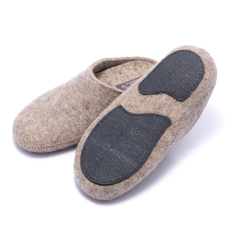 May include: A pair of beige wool slippers with black rubber soles. The slippers are made of a soft, comfortable material and have a simple, classic design.
