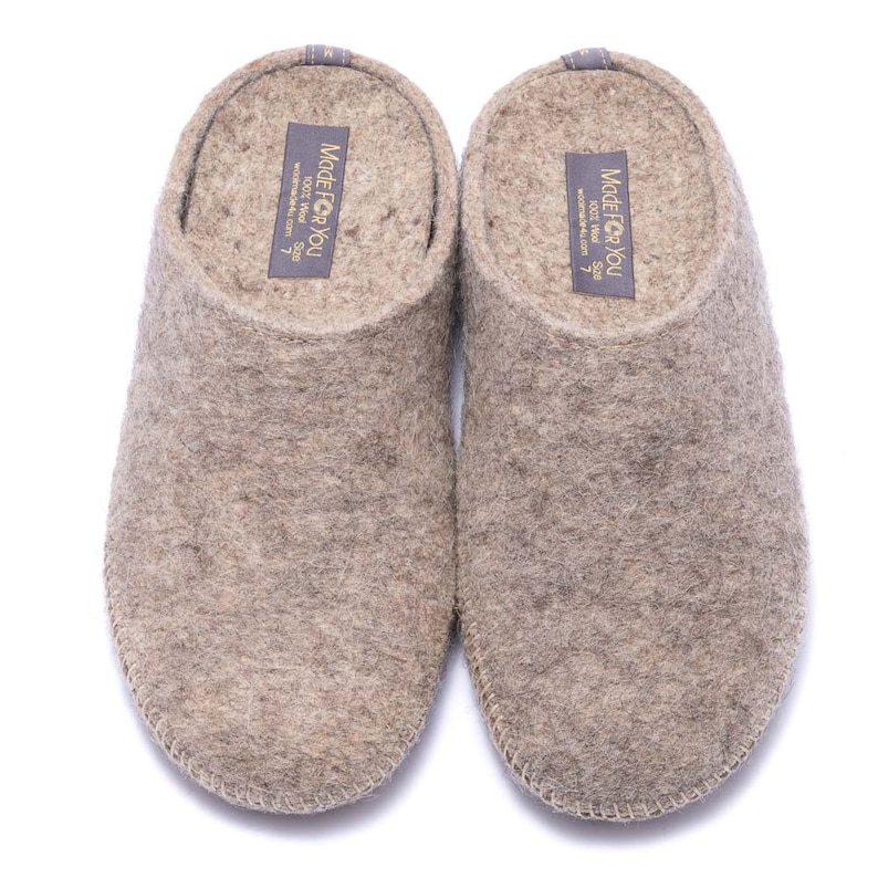 May include: A pair of gray wool slippers with a brown leather trim. The slippers have a label on the top that says "Made for You 100% Wool Size 7 www.madeforyou.com".