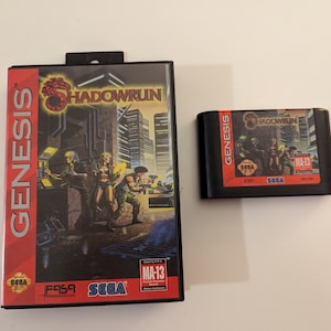 May include: A Sega Genesis video game cartridge and case for Shadowrun. The case features a futuristic cityscape with characters holding weapons. The cartridge is black with a red and orange label. The game is rated MA-13.