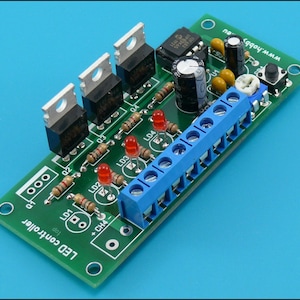 Könnte beinhalten: Eine grüne Leiterplatte mit dem Text "LED controller" darauf gedruckt. Die Platine hat drei LEDs, drei Widerstände und einen kleinen Knopf. Die Platine ist mit einer blauen Klemmenleiste verbunden.