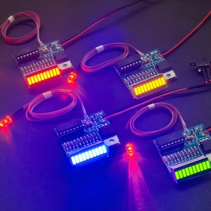 May include: Four electronic circuit boards with LED bar graph displays and connected LED lights. The displays show illuminated segments in red, yellow, blue, and green. Each board features integrated circuits, resistors, and thin wiring.