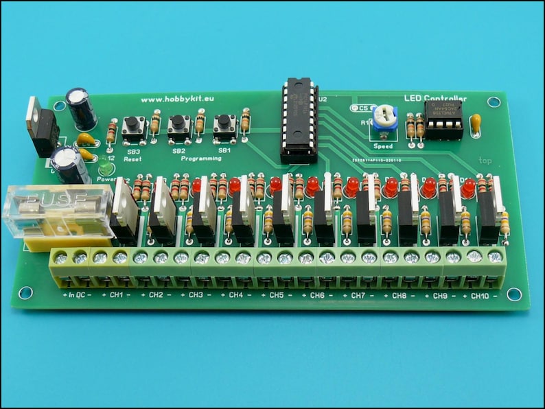 May include: A green circuit board with an LED controller, 10 channels, and a speed control knob. The board has a fuse, reset button, and programming buttons. The text "www.hobbykit.eu" is printed on the board.