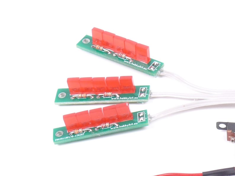 May include: Three green circuit boards with red components and white wires. Each board has a row of red rectangular pieces. The boards are arranged on a white background. The text "www.hobbykit.eu" is visible on the boards.