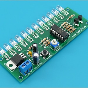 Puede incluir: Una placa de circuito verde con múltiples componentes electrónicos, incluyendo luces LED transparentes, resistencias y un circuito integrado negro. Tiene un bloque de terminales azul y un potenciómetro "Speed". El texto "www.hobbykit.eu" es visible.