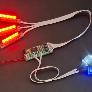 May include: Electronic circuit board with red and blue LED lights. Three red LED light strips are connected to the circuit board with white ribbon cables. Two individual LEDs, one blue and one white, are also connected.