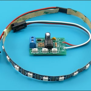 May include: A green electronic circuit board controller with three white push buttons labeled Programs, Color, and Speed, connected to a flexible black LED light strip with red, white, and green wires and a black connector plug.
