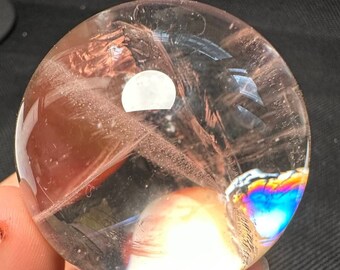 May include: A clear quartz crystal ball with iridescent rainbow colours and a white cloudy interior.
