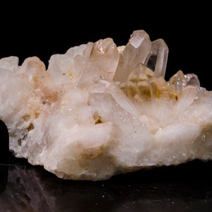 以下が含まれることがあります： 乳白色のベースに透明な水晶のクラスター。結晶はランダムなパターンで配置されており、自然で粗い質感があります。