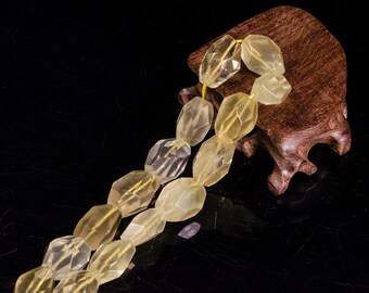 May include: A strand of faceted, light yellow citrine beads on a wooden stand. The beads are oval shaped and have a translucent appearance.