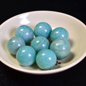 May include: A bowl of eight smooth, round, teal green amazonite spheres.