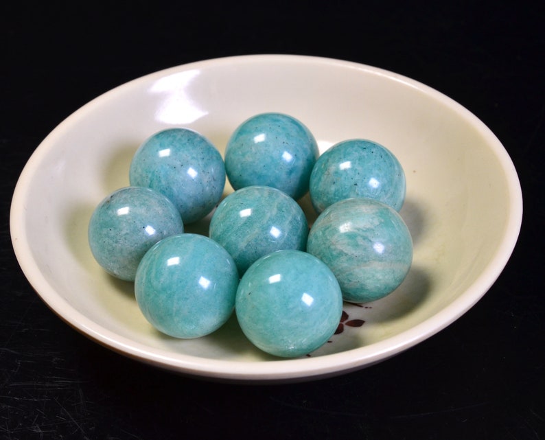 May include: A bowl of eight smooth, round, teal green amazonite spheres.
