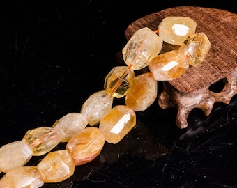 May include: A strand of faceted, yellow citrine beads, strung on a thin orange thread. The beads are oval-shaped and have a translucent, glassy appearance. The beads are displayed on a small wooden stand.