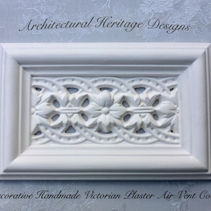 May include: White plaster air vent cover with an intricate Victorian design. The cover is rectangular and has a raised border. "Architectural Heritage Designs" is written above the vent cover and "Decorative Handmade Victorian Plaster Air Vent Cover" is written below.