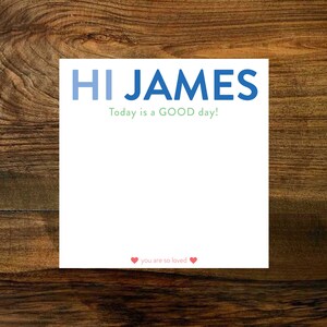 May include: White card with blue text that says "HI JAMES" and green text that says "Today is a GOOD day!"  There are two red hearts at the bottom with the text "you are so loved".