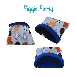 May include: Blue and white fabric guinea pig sleeping bag with a blue fleece lining. The fabric has a pattern of cartoon guinea pigs. The sleeping bag is labeled "Piggie Party".