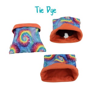 May include: Tie dye pet bed with a bright blue, orange, yellow, and pink swirl pattern. The bed is made of soft fleece and has a bright orange lining.