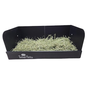 May include: A black plastic hay rack for small pets, filled with green hay. The rack has a TaterPets logo on the front.