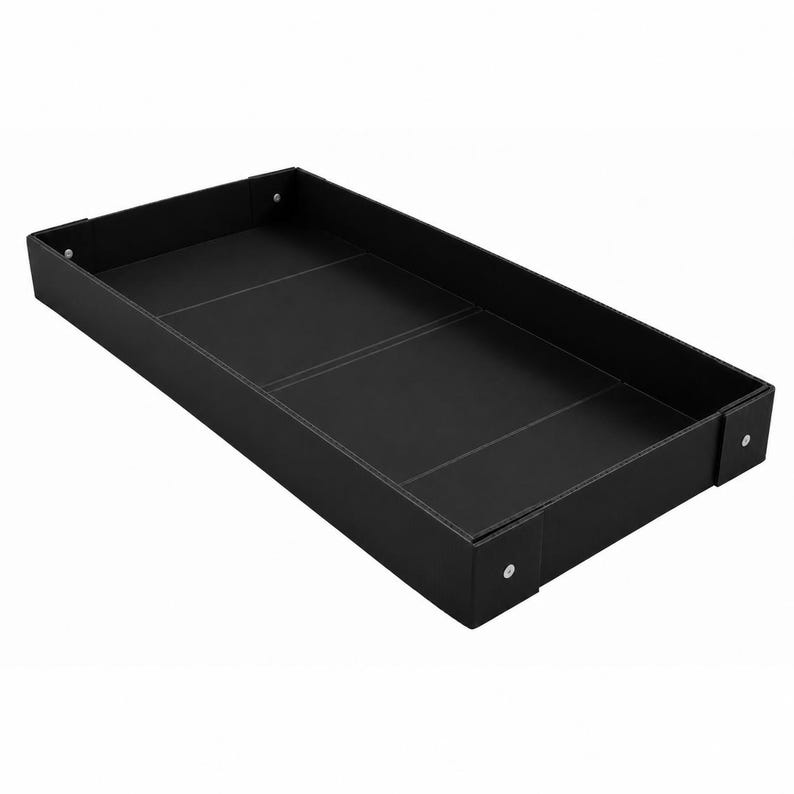 May include: A rectangular black tray with a smooth surface and raised edges. The tray features visible white stitching along the seams and corners, with small silver-toned metal rivets securing the corners of the frame to the base structure.