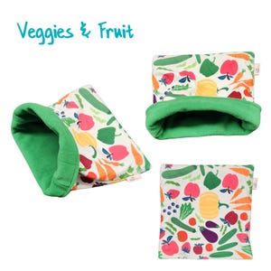 May include: A green and white fabric pet bed with a colorful print of vegetables and fruit. The bed is shaped like a cylinder and has a green fleece lining. The text "Veggies & Fruit" is printed on the image.