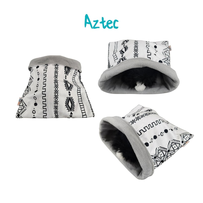 May include: A white and black patterned pet bed with a gray fleece lining. The bed is shaped like a cylinder and has a geometric design. The text "Aztec" is written in blue above the bed.