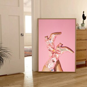 May include: A framed print of a pair of pink cowboy boots with floral patterns on a pink background.