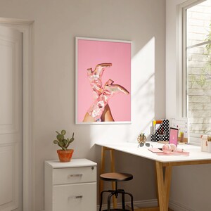 May include: A framed print of a pair of pink cowboy boots on a pink background.