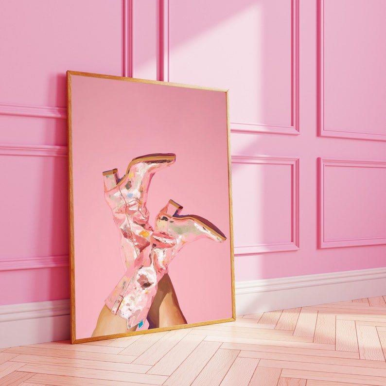 May include: A framed print of a pair of pink cowboy boots with floral details against a pink background.