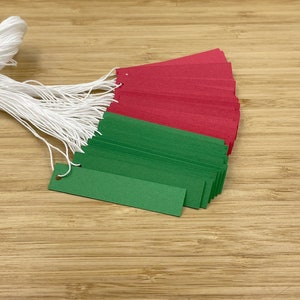 May include: A bundle of green and red paper tags with white string attached. The tags are arranged in a fan shape.