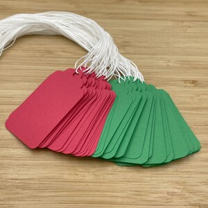 May include: A stack of red and green gift tags with white string attached. The tags are blank and ready to be written on.