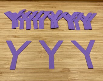 Puede incluir: Un conjunto de letras Y de papel morado. Hay 18 letras Y pequeñas y 3 letras Y más grandes.